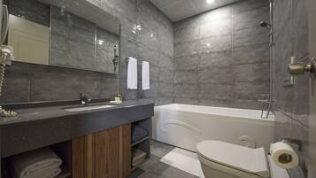 Un baño moderno con un espejo grande, una bañera y un inodoro.