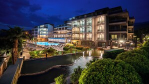 A multi-story hotel with a swimming pool, outdoor seating, and lush greenery. - Hierapark Thermal & Spa Hotel (Denizli)