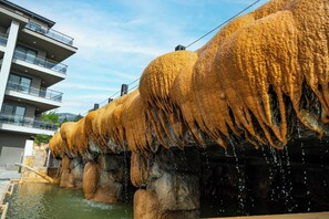 A water feature with cascading water over textured rock formations. - Hierapark Thermal & Spa Hotel (Denizli)