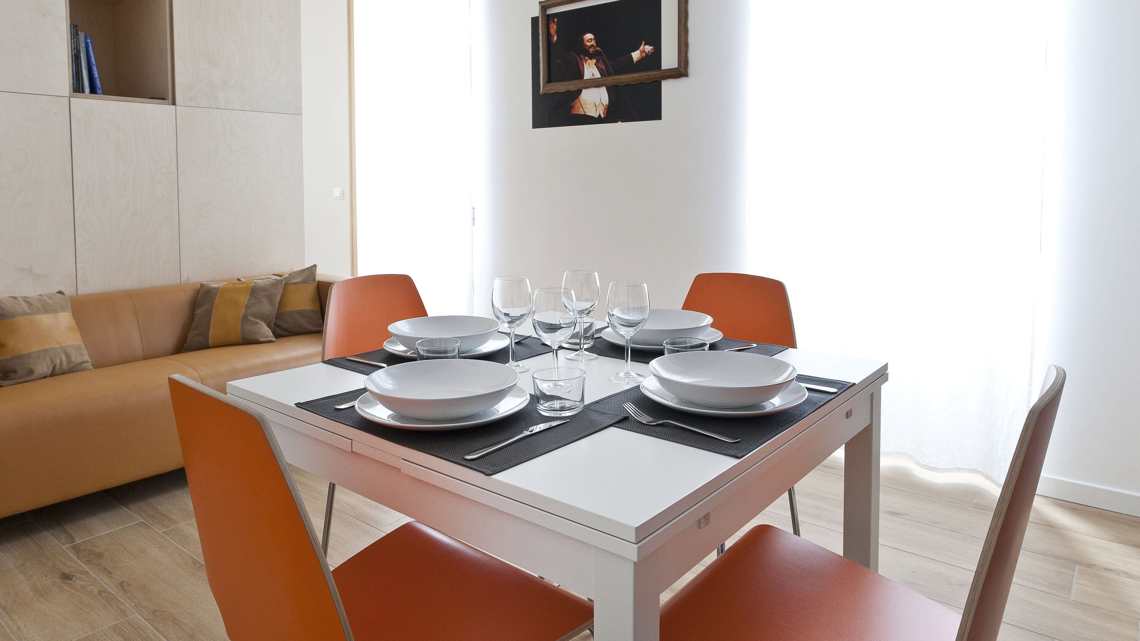 Comedor con una mesa dispuesta para cuatro personas, incluyendo platos, vasos y cubiertos.