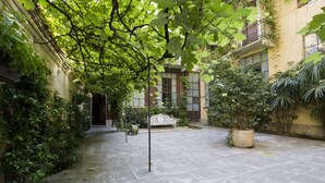 A courtyard with a bench, surrounded by lush greenery and a tiled floor. - Italianway   - Caretto (Milan)