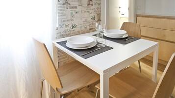 A dining table set with plates, glasses, and cutlery, with a patterned wallpaper in the background.