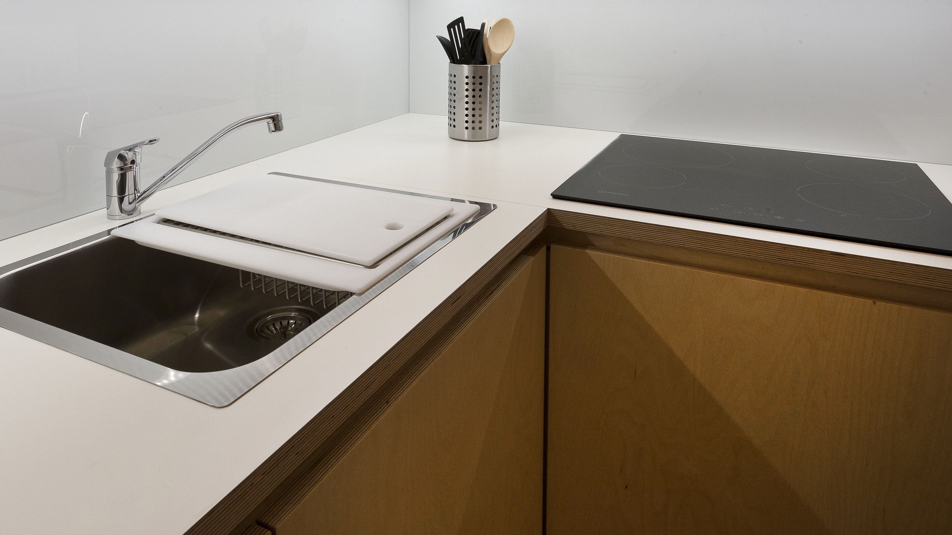 Una cocina moderna con un lavamanos de acero inoxidable, una tabla de cortar y un recipiente para utensilios.