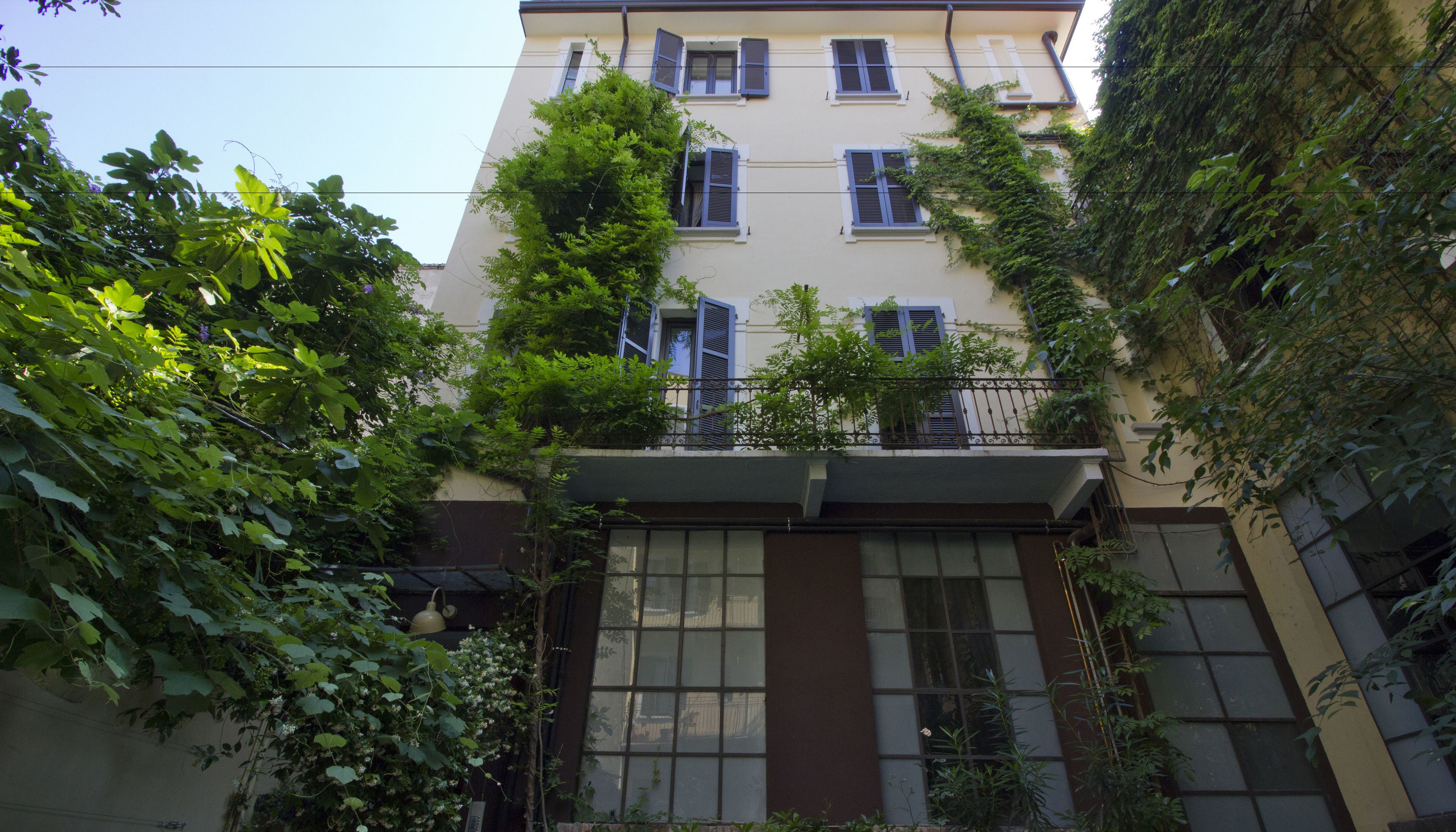 A multi-story building with a balcony and a window with a curtain.
