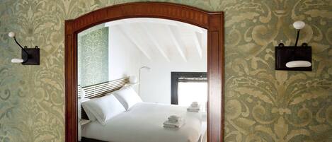 A bedroom with a bed, a mirror, and a wall-mounted light fixture.
