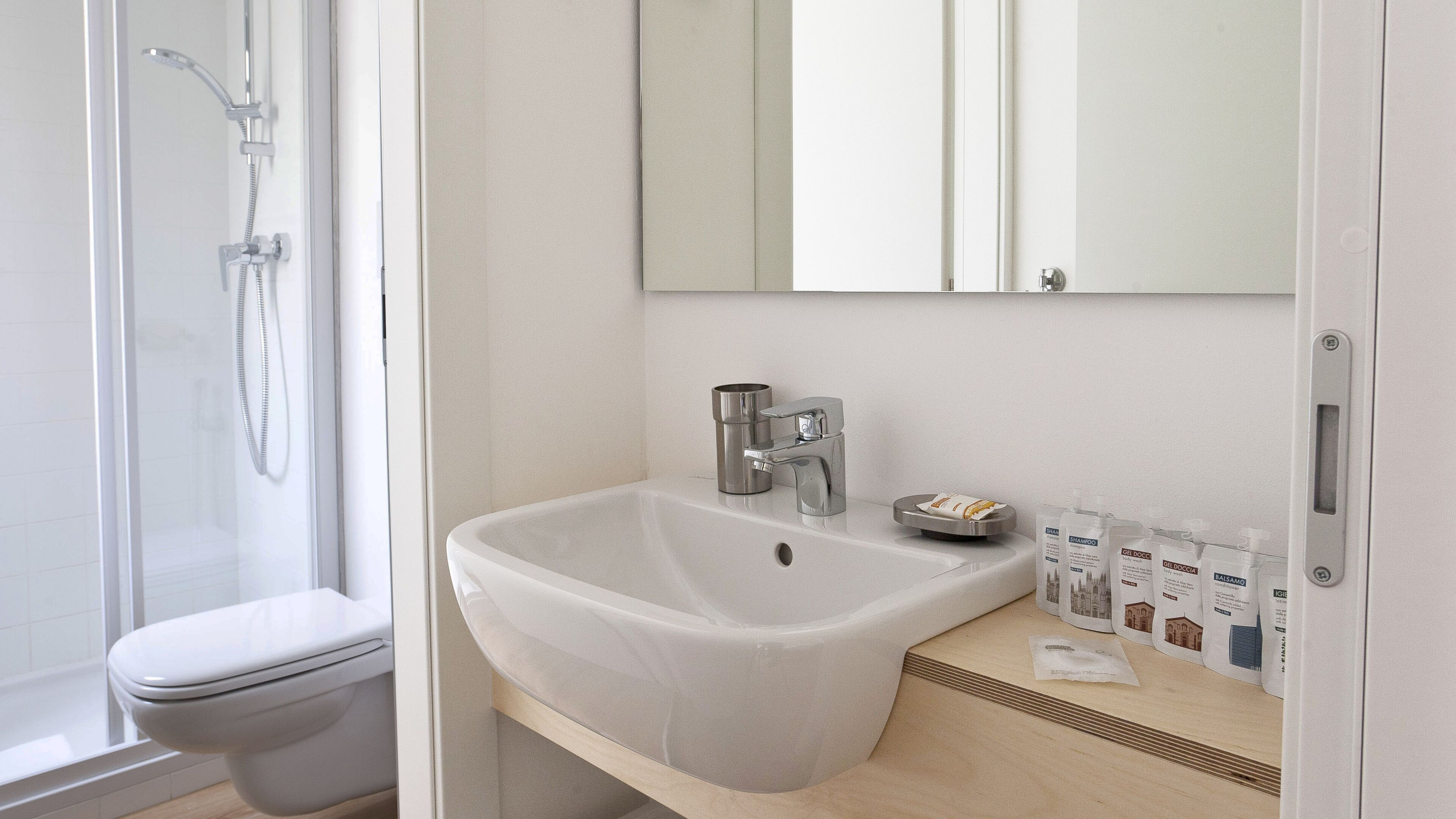 A bathroom with a white sink, a mirror, and toiletries.