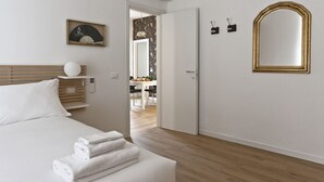 A hotel room with a bed, a bedside table, a wall-mounted mirror, and a door leading to a dining area. - Italianway   - Caretto (Milan)