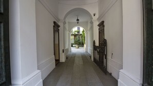 A corridor with white walls and a tiled floor, leading to a balcony with a view of greenery. - Italianway   - Caretto (Milan)