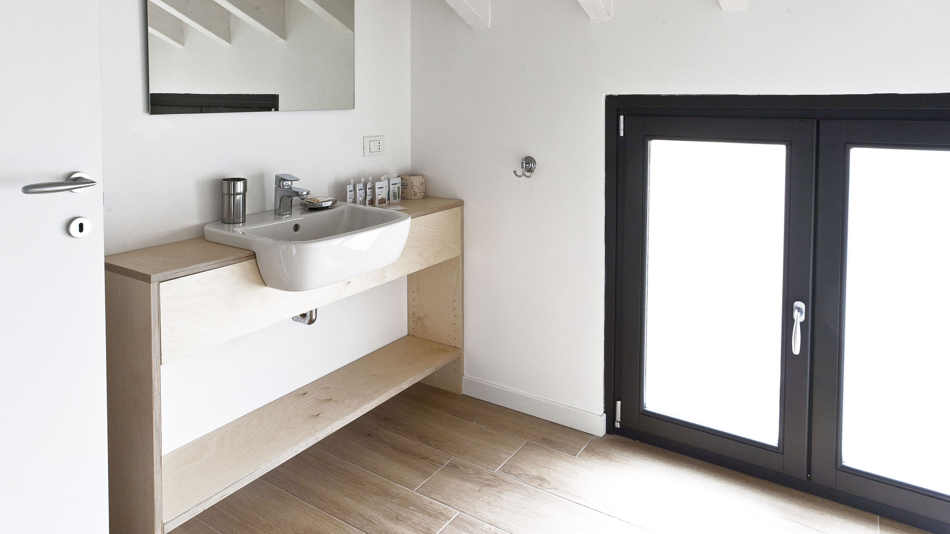 Une salle de bain moderne avec un grand lavabo, un miroir et une porte à cadre noir.