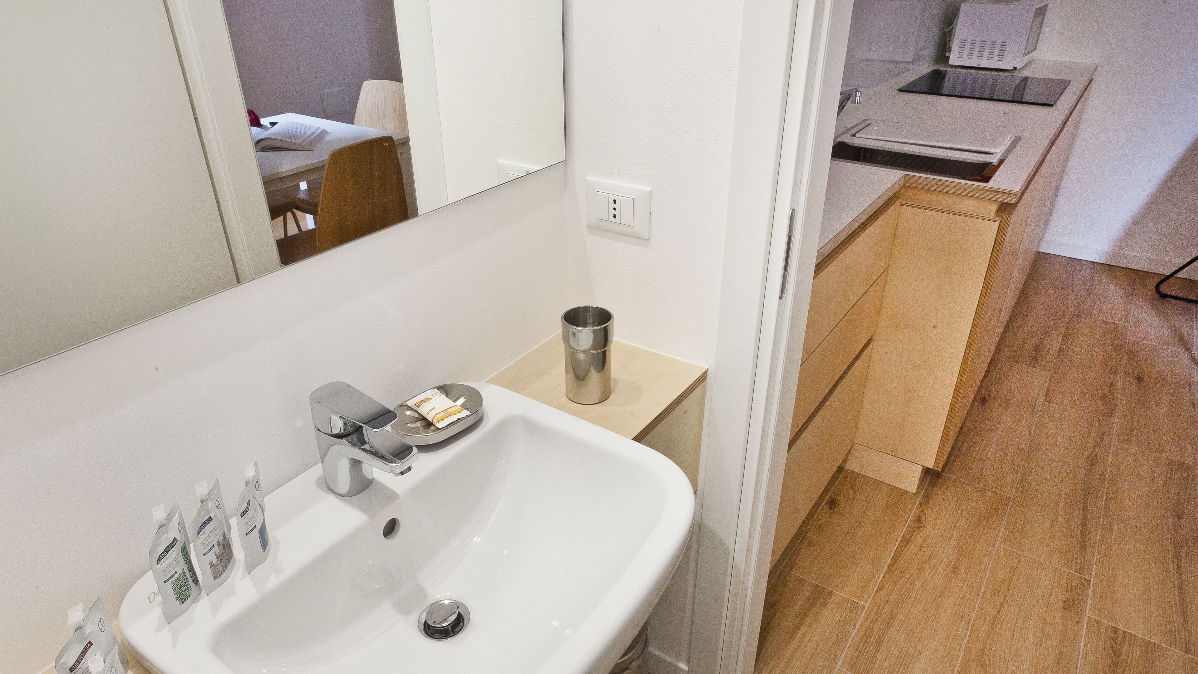 A bathroom with a white sink, a mirror, and a small wooden cabinet.