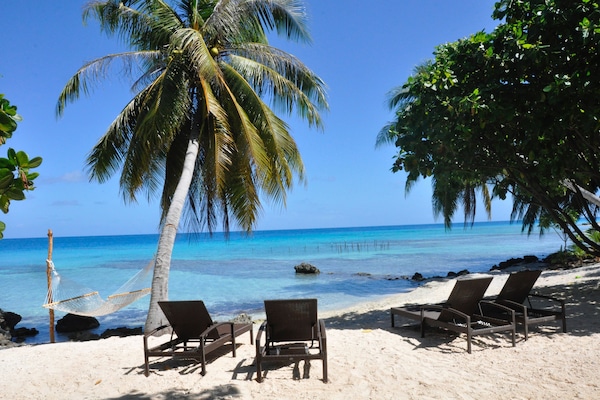 Aan een privéstrand, wit zand, ligstoelen, strandlakens