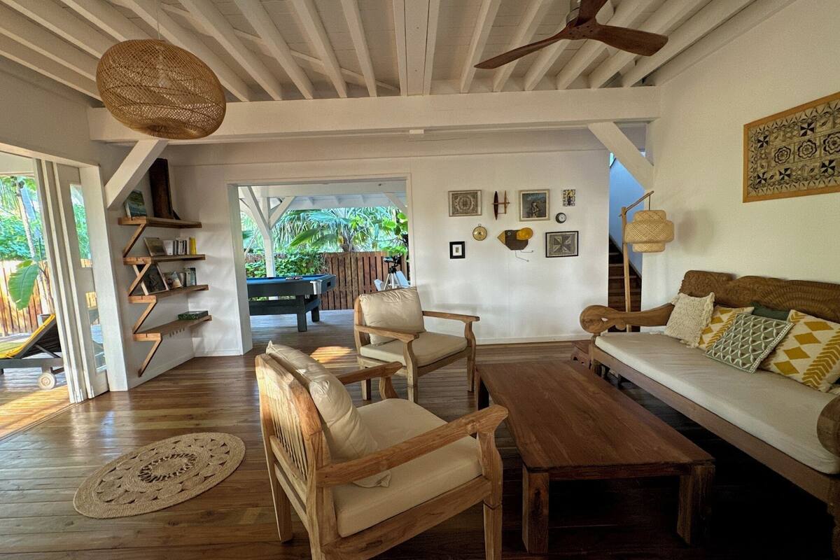Uma sala de estar ampla com móveis de madeira, mesa de bilhar e ventilador de teto.