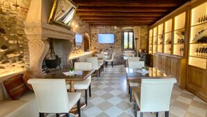 Un comedor acogedor con suelo de cuadros, paredes de piedra, vigas de madera y una chimenea.
