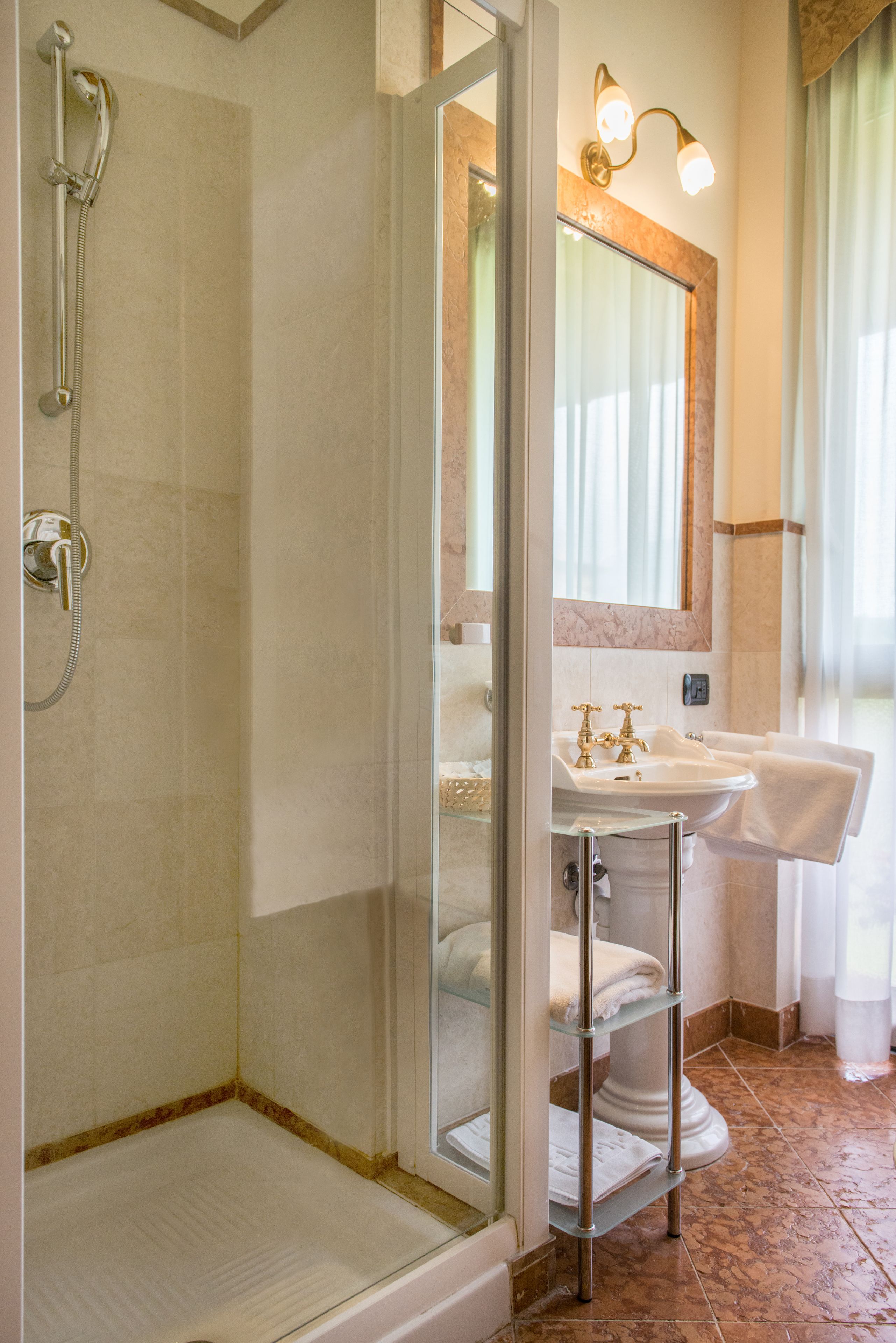 Une salle de bain avec une douche à parois de verre, un lavabo doté d’un plan de travail en marbre et un porte-serviettes.