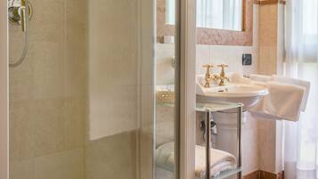 Une salle de bain avec une douche à parois de verre, un lavabo doté d’un plan de travail en marbre et un porte-serviettes.