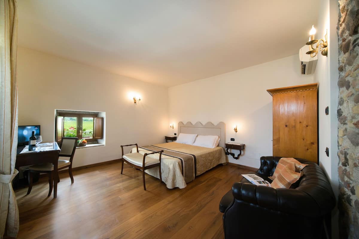 Een slaapkamer met een bed, een bureau met een computer, een stoel, een raam met uitzicht en een houten kast.