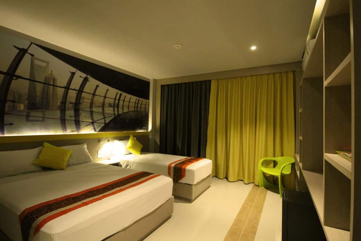 Habitación de hotel con dos camas, un ventanal con vista a la ciudad, una silla verde y un armario.