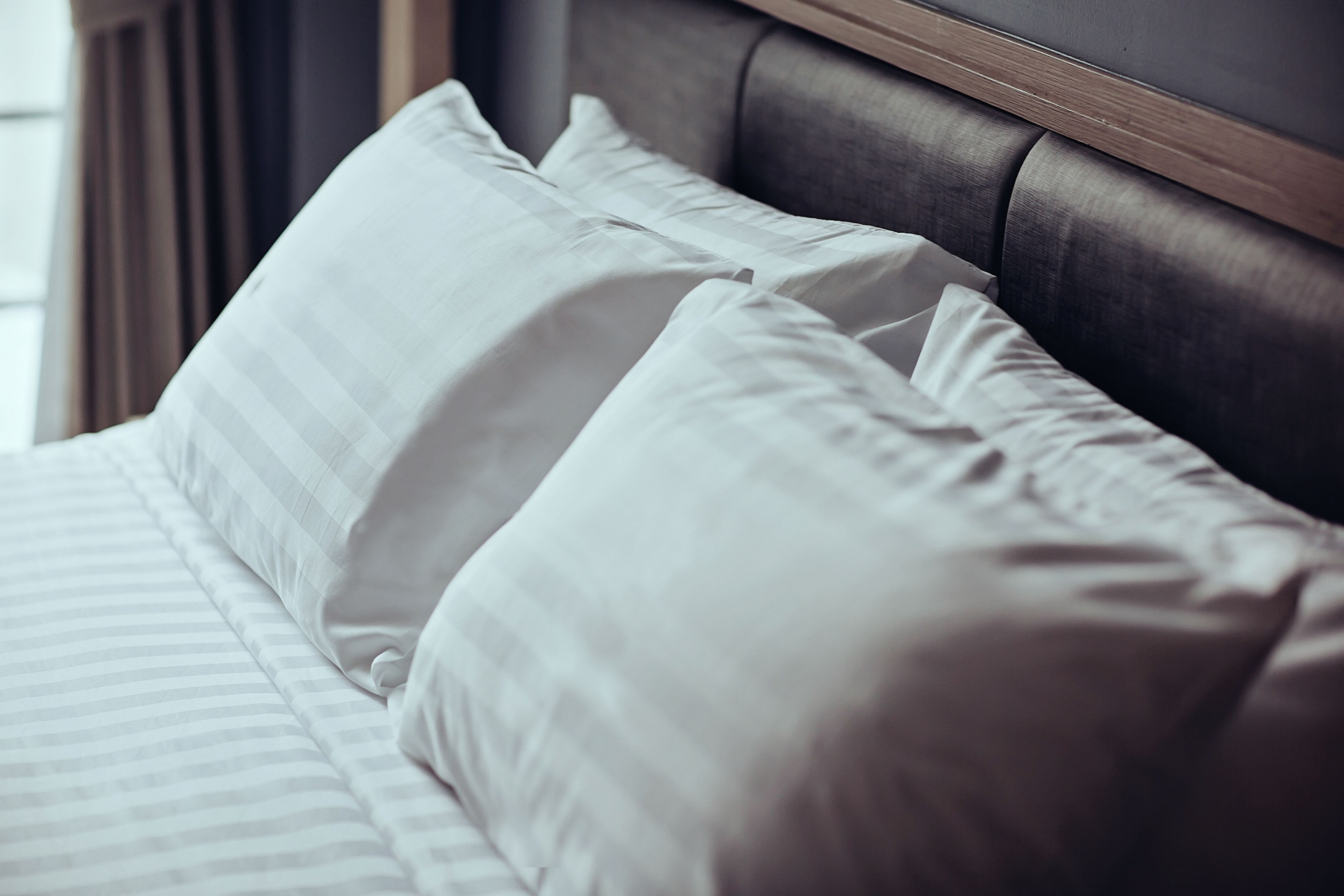 A bed with white bedding and a wooden headboard.