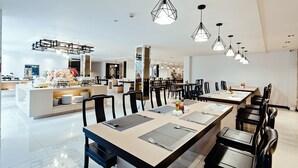 A modern dining area with long tables, black chairs, and geometric pendant lights. - Three Sukhumvit Hotel (Bangkok)