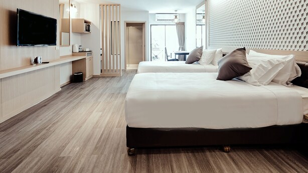 A modern hotel room with a large bed, a TV mounted on the wall, a microwave, and a small table with a chair. - Three Sukhumvit Hotel (Bangkok)