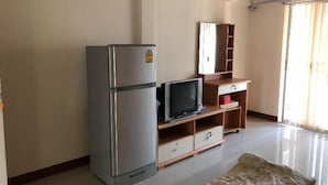 A compact living space with a refrigerator, a flat-screen TV, a wooden cabinet, and a sofa. - BB Place (Bangkok)