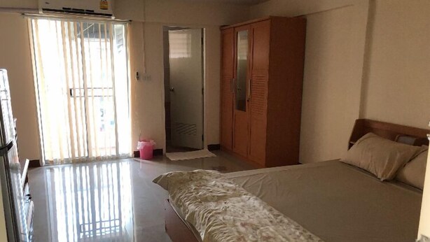 A hotel room with a bed, a wardrobe, a door, and a window with blinds. - BB Place (Bangkok)