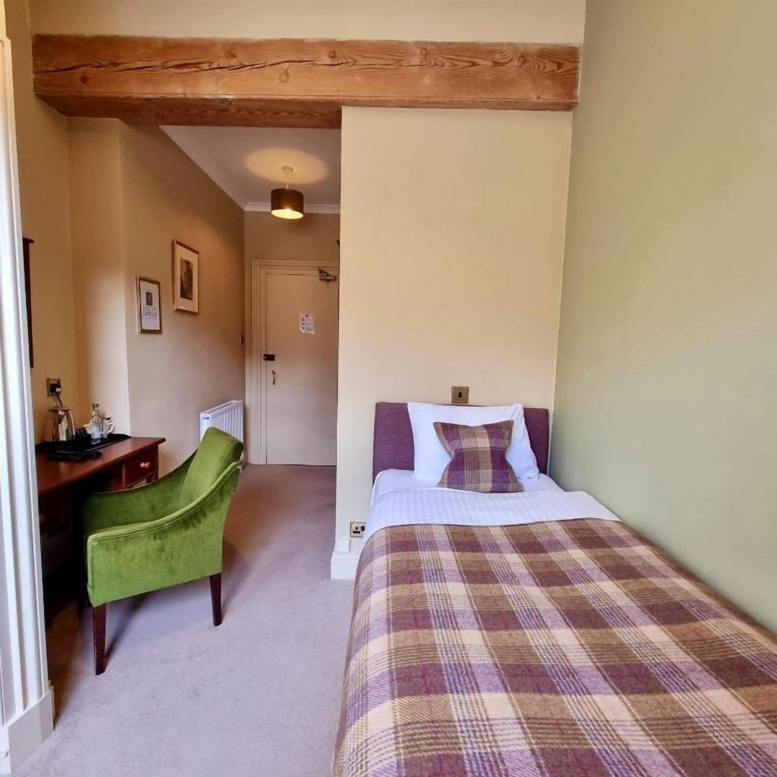 A bedroom with a bed, a desk, and a chair.
