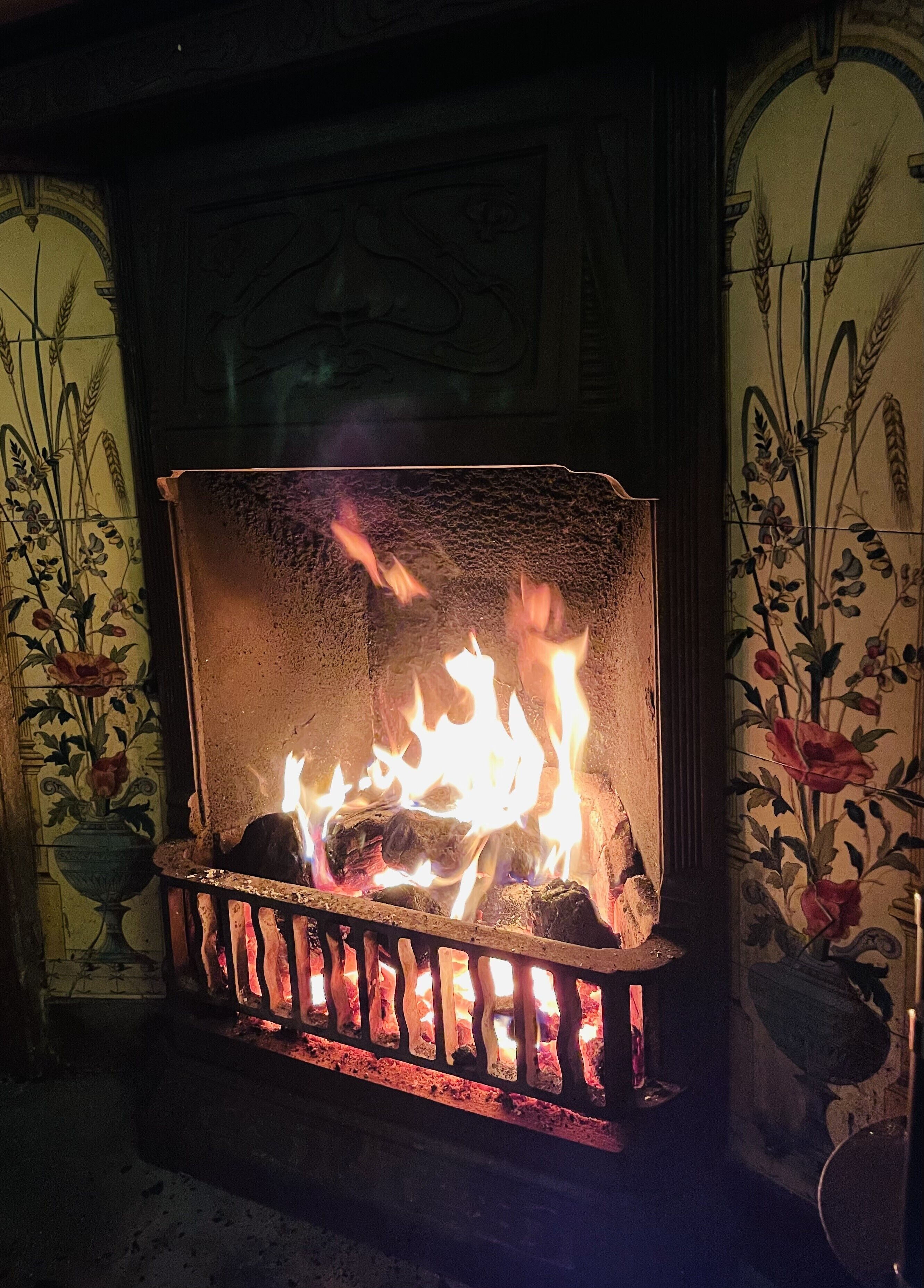A fireplace with a fire burning inside, surrounded by ornate wall decorations.