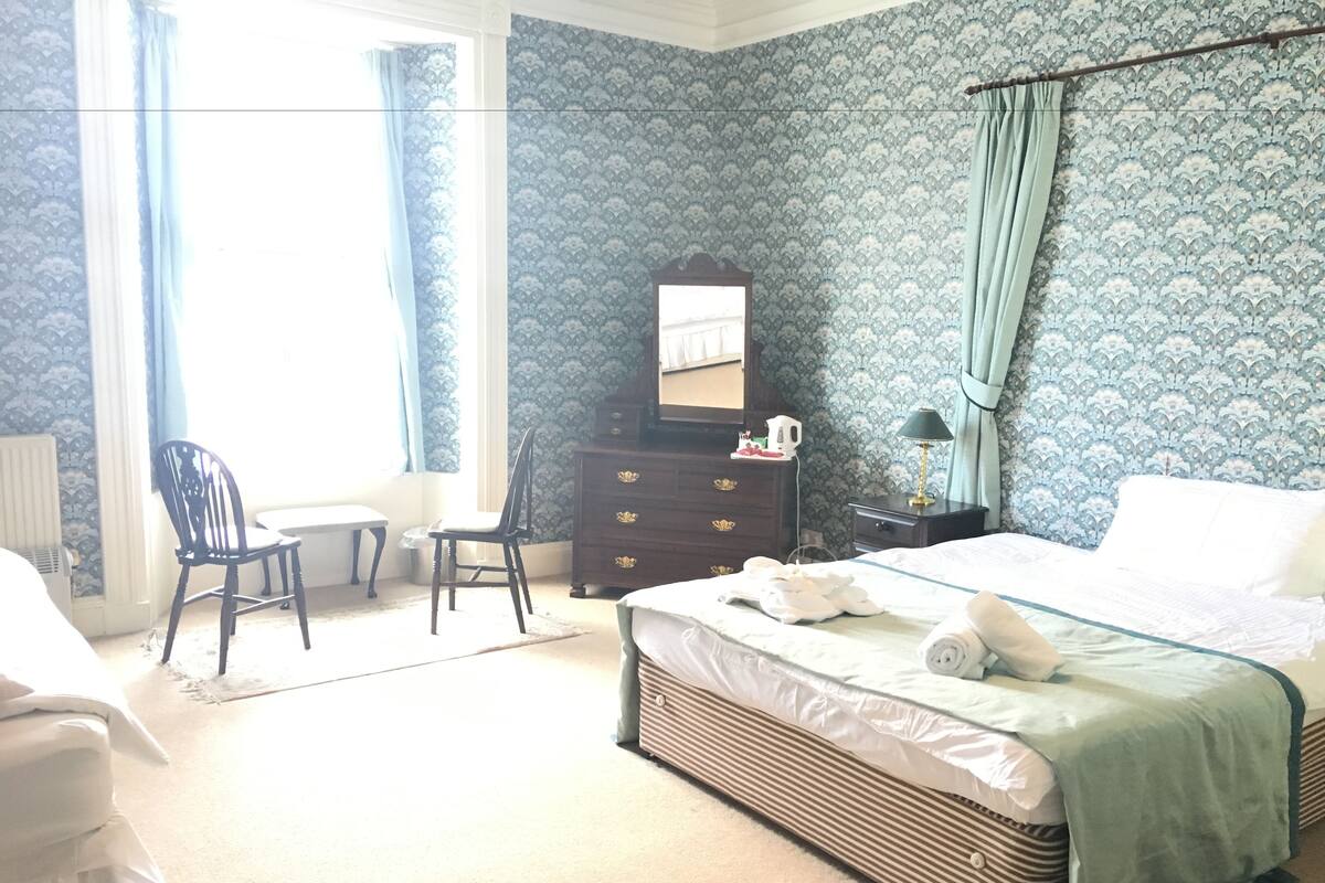 Une chambre à coucher avec un lit, une commode, une chaise et un bureau.