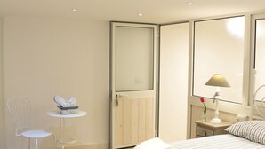 Quarto com cama, cadeira, mesinha, abajur e espelho.