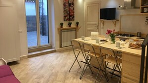 Cozinha compacta com área de refeições, TV integrada e vista pela porta de correr.