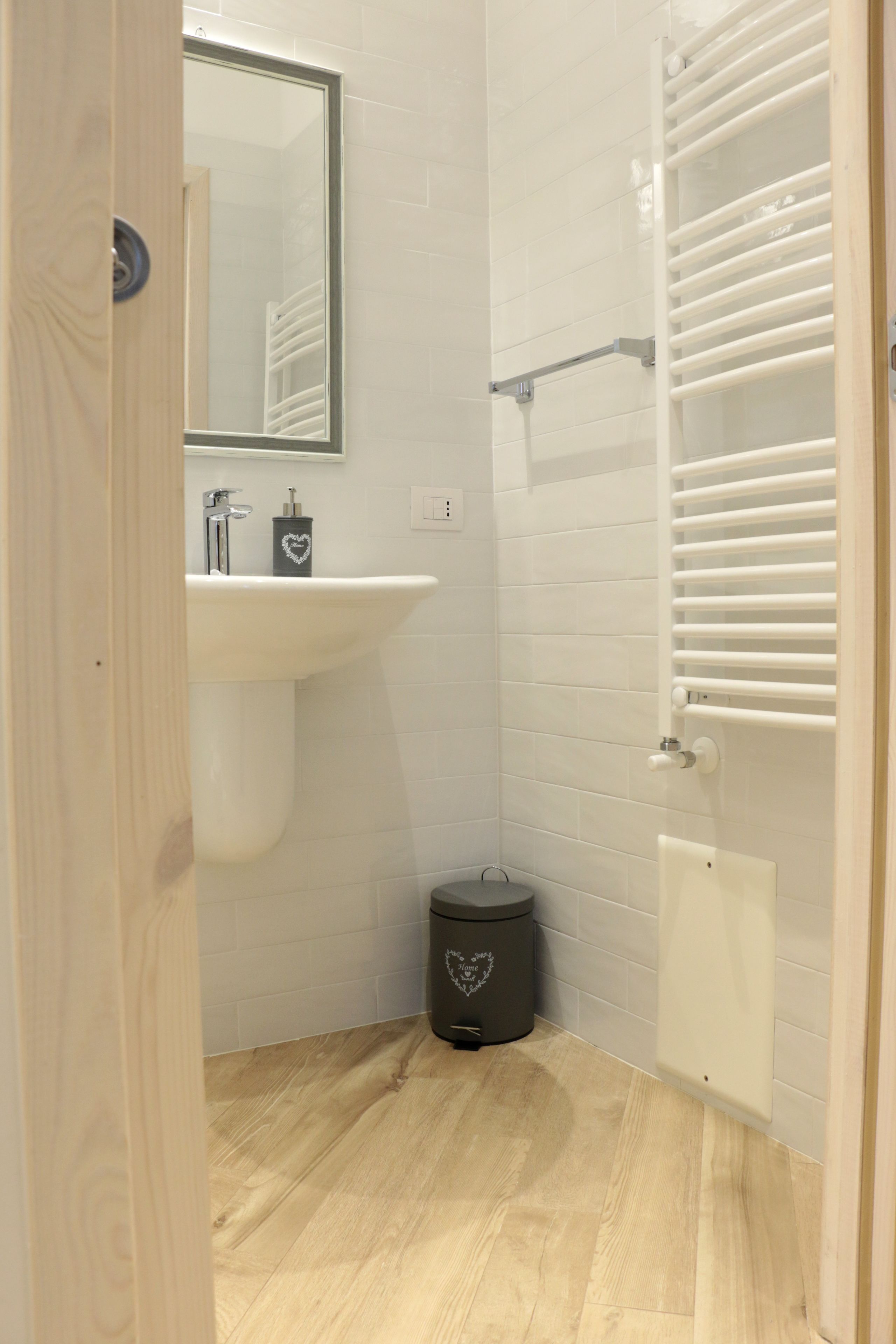 Un baño pequeño con lavamanos, espejo y toallero blancos.
