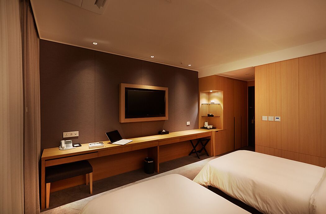 Une chambre d’hôtel avec un lit, un bureau avec un ordinateur portable, une télévision et une table de chevet.