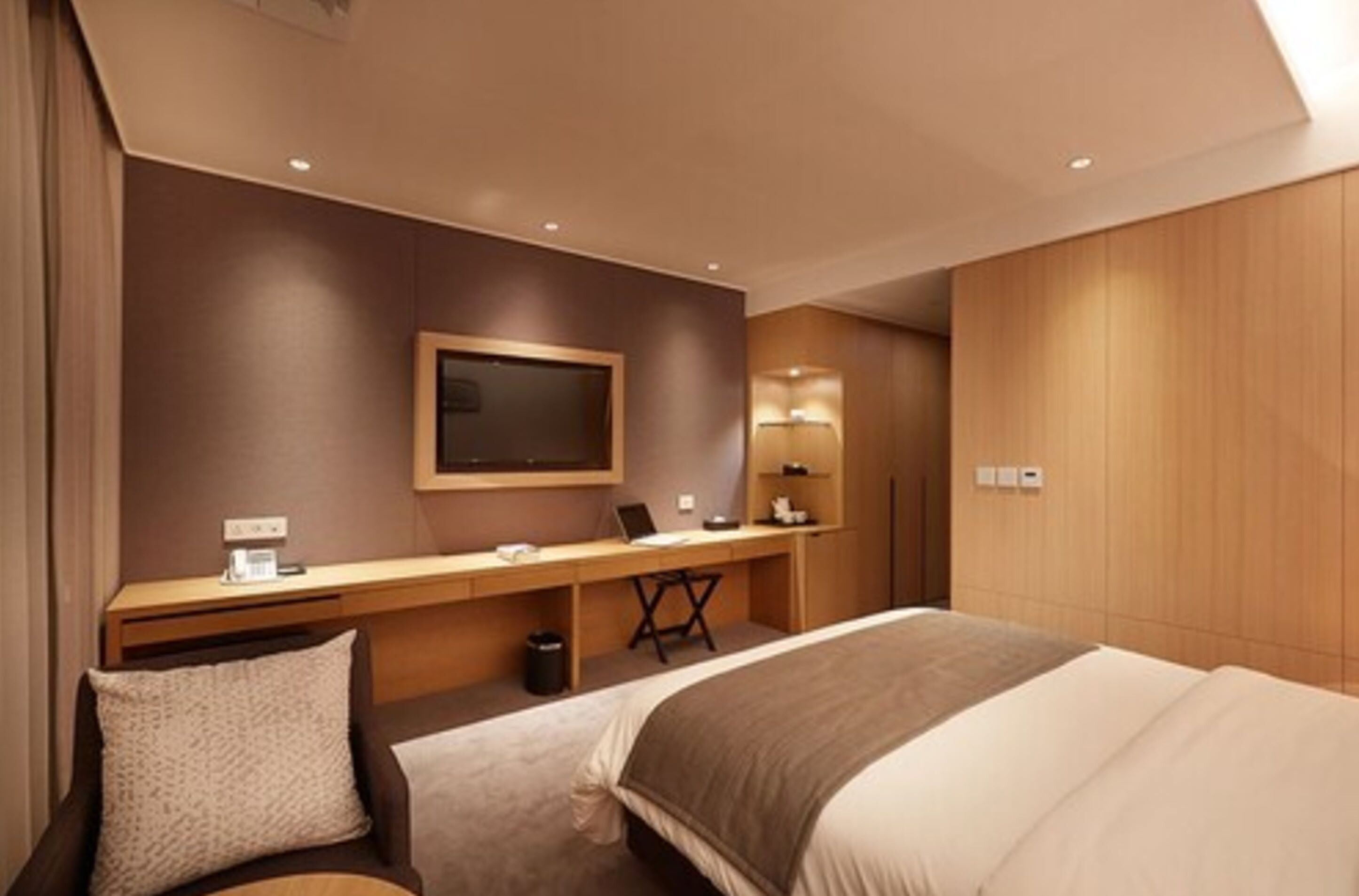 Une chambre d’hôtel moderne avec un grand lit, un bureau équipé d’un ordinateur, une télévision et une lampe.