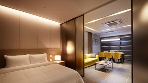 Une chambre d’hôtel avec un grand lit, un bureau avec une chaise, un canapé et une petite table.