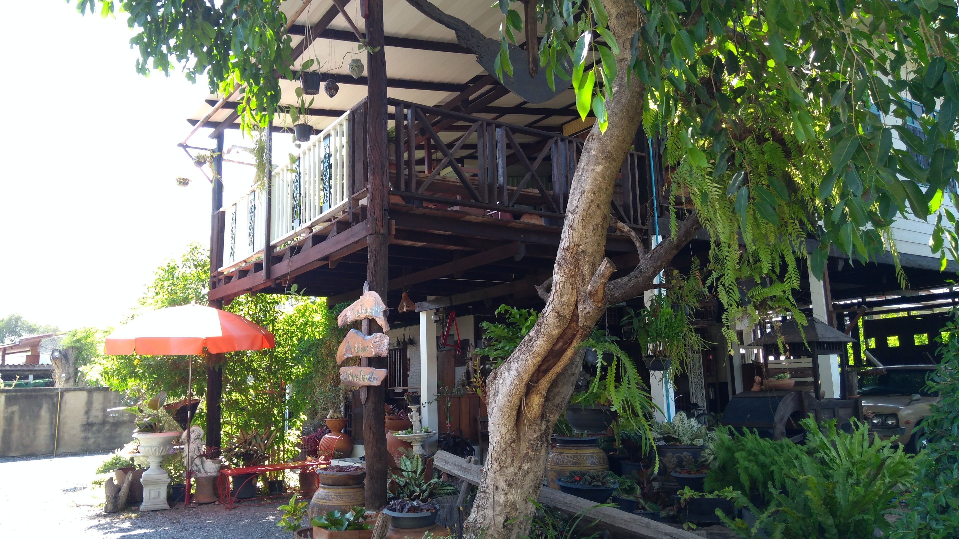 A covered outdoor area with a wooden deck, potted plants, and a red umbrella.