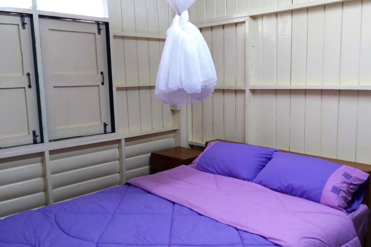 Ein Zimmer mit einem Bett, einem Holzschrank und einem Moskitonetz.