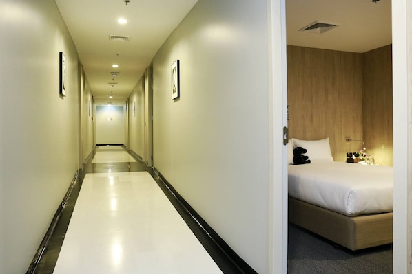 Un pasillo de hotel con una cama en la habitación a la derecha.