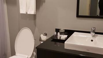 A modern bathroom with a white toilet, a black sink, and a mirror above the sink.