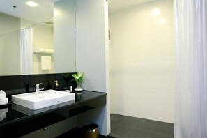 A modern bathroom with a white sink, black countertop, and a shower area. - Sleep Box by Miracle (Bangkok)