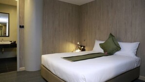 Habitación de hotel con una cama grande, una mesita de noche con lámpara y un espejo en la pared.