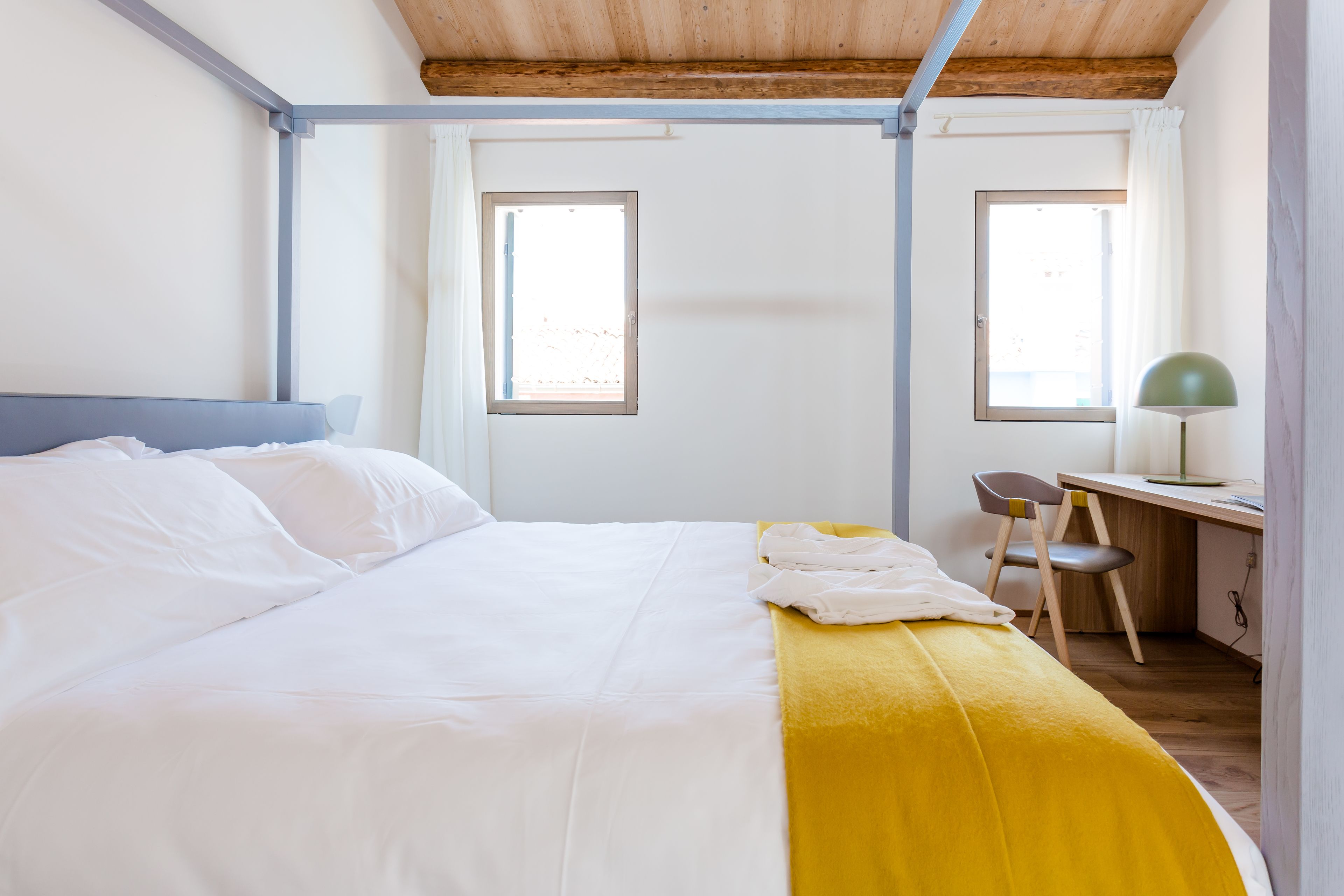 Ein Schlafzimmer mit einem Bett, einem Schreibtisch und zwei Fenstern.