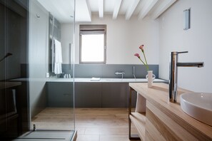 A modern bathroom with a wooden vanity, a large sink, and a glass shower enclosure.