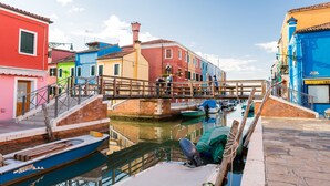 Un canal con barcos amarrados, un puente de madera y edificios coloridos a lo largo del agua.