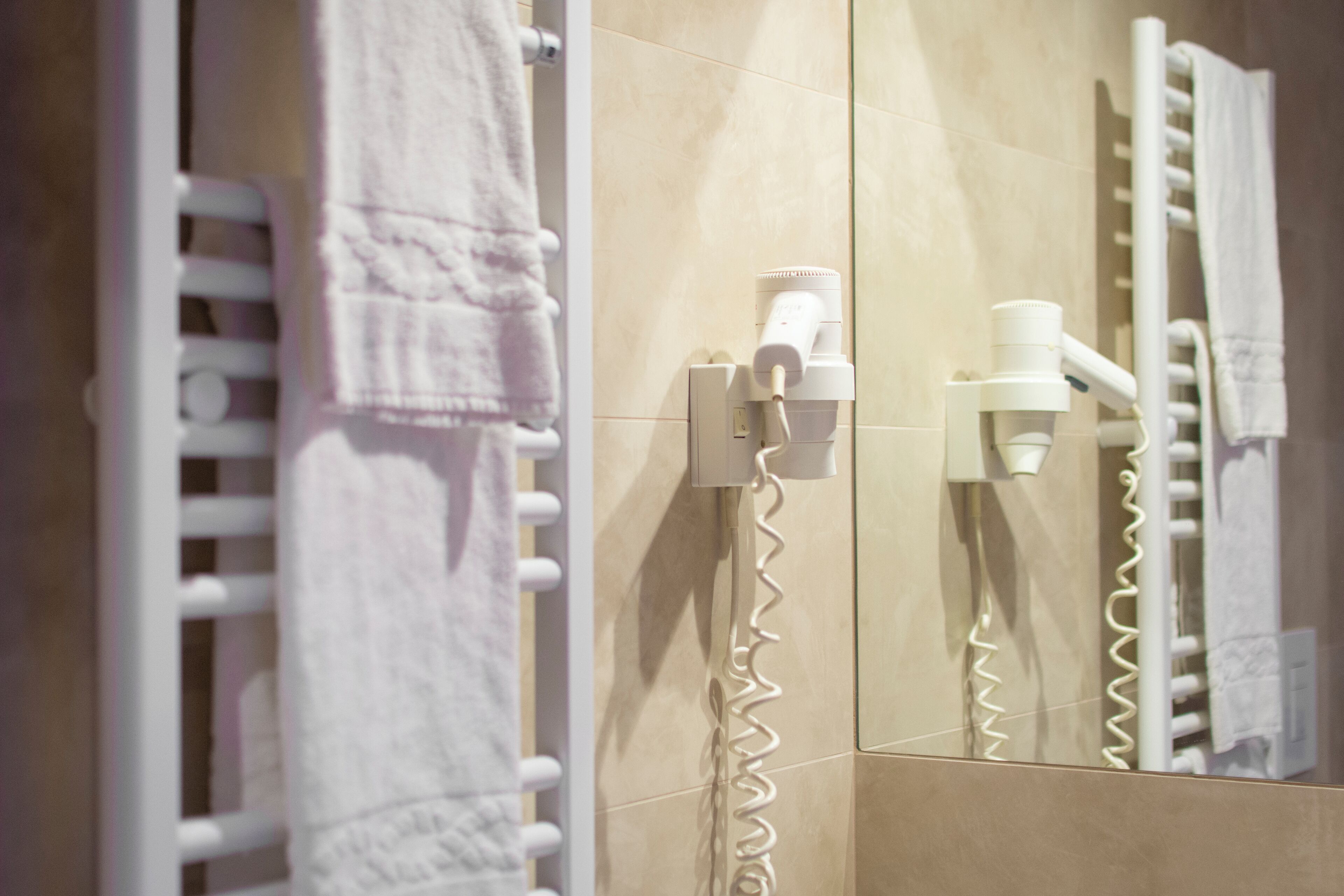 A bathroom with a towel rack, a hairdryer, and a mirror.