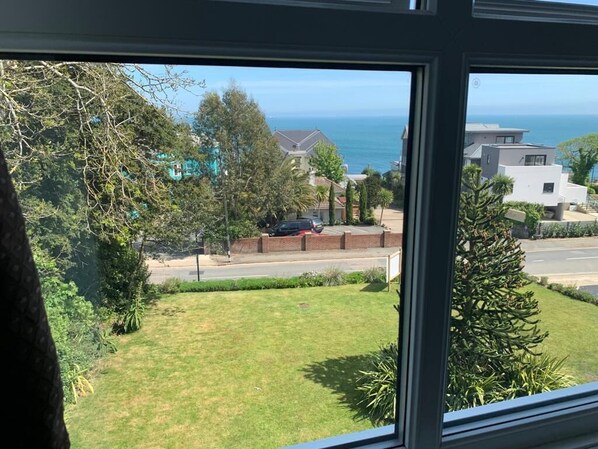 A view from a window overlooking a grassy area, a road, and a body of water.