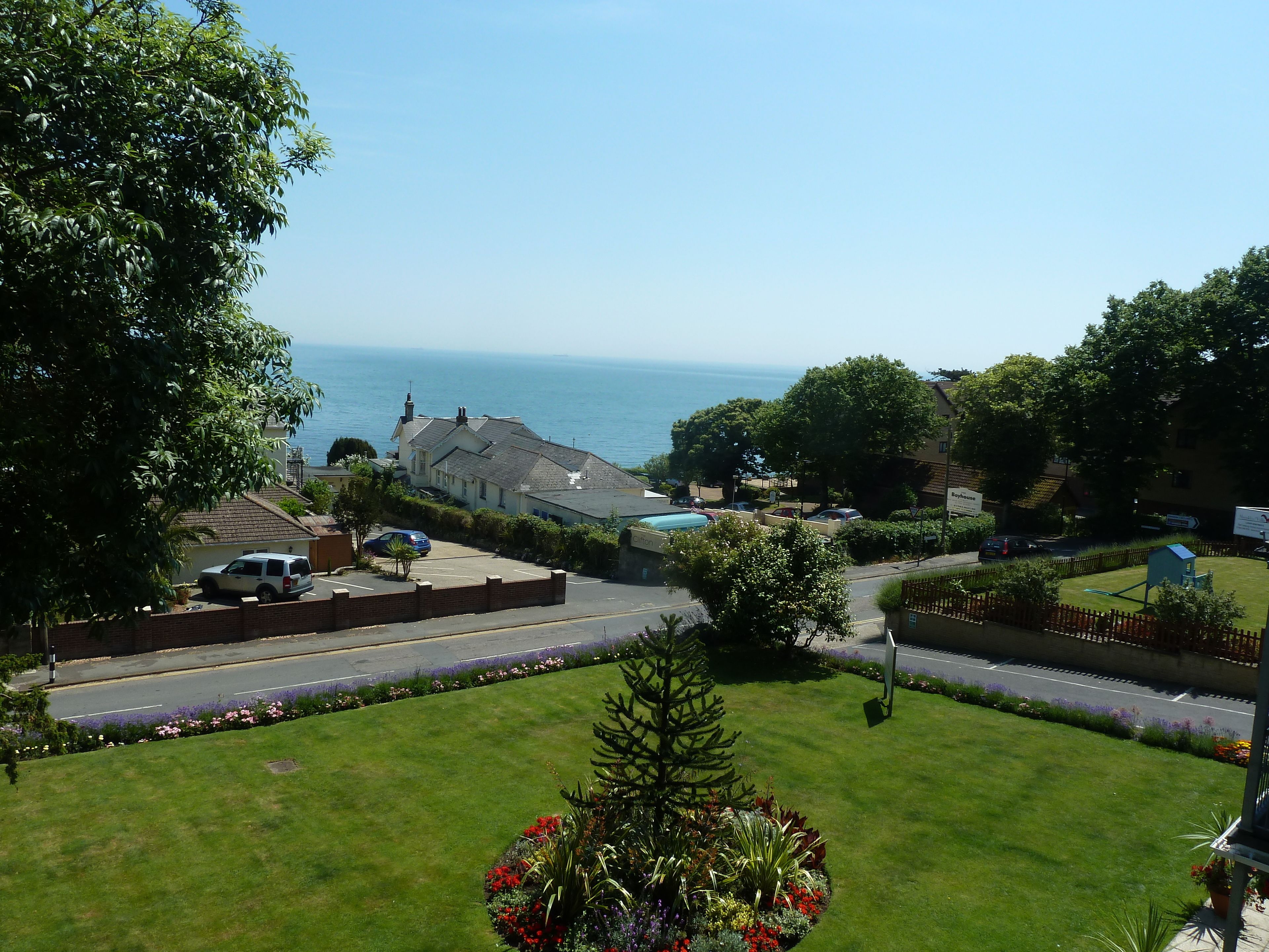 A residential area with a view of the sea, houses, and a parking lot.