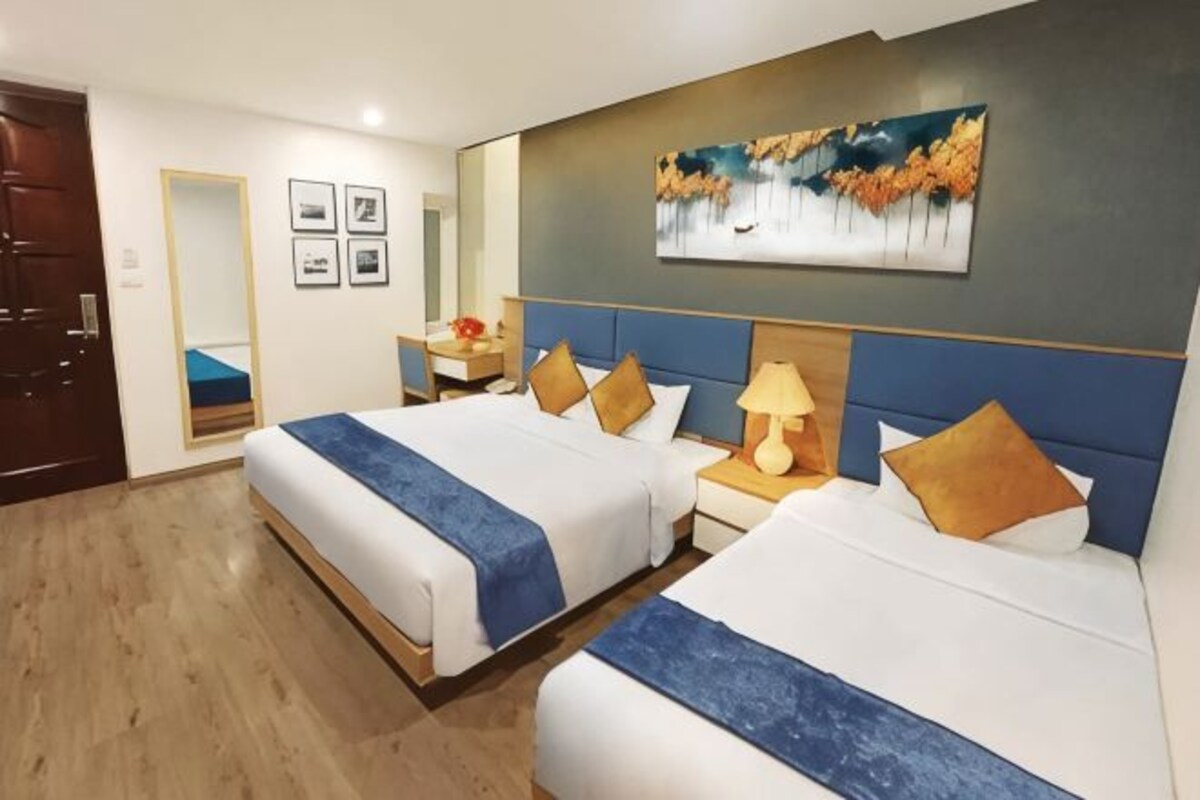Een hotelkamer met twee bedden, een bureau en een schilderij aan de muur.