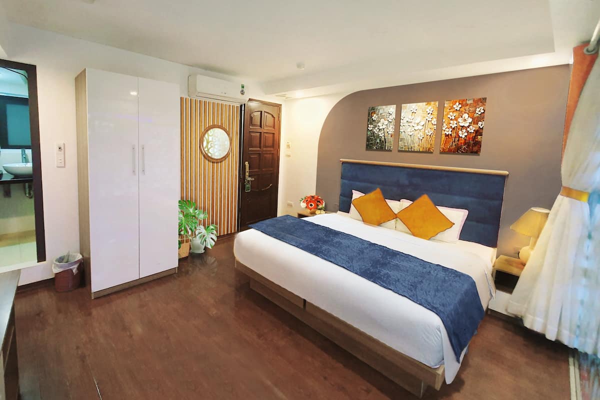 Een slaapkamer met een groot bed, een kledingkast, een spiegel en een deur.