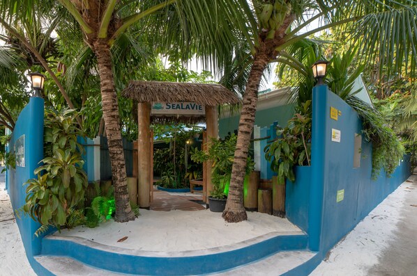 A beachside entrance with a sign reading "Sealavie," surrounded by palm trees and tropical plants.
